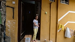 طفلة عراقية تقف على عتبة منزل ذويها وإلى جانبها سلة مساعدات غذائية تقدمة الجمعيات الخيرية في مدينة الموصل شمال البلاد خلال شهر رمضان المبارك