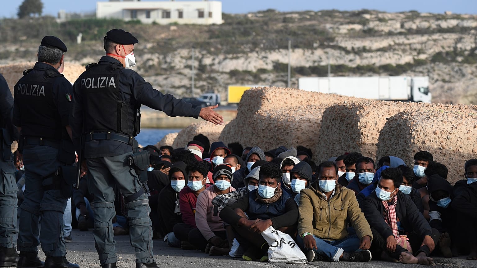 Les migrants arrivés sur l'île de Lampedusa en Italie attendent sur le quai, le 10 mai 2021