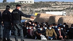 Les migrants arrivés sur l'île de Lampedusa en Italie attendent sur le quai, le 10 mai 2021