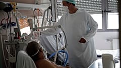 أحد أعضاء الطاقم الطبي يعتني بمريض مصاب بفيروس كورونا في وحدة العناية المركزة في مستشفى شارل نيكول العام في روان - فرنسا