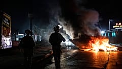 Firefighters inspect destroyed buildings after it was hit by Israeli airstrikes, in Gaza City