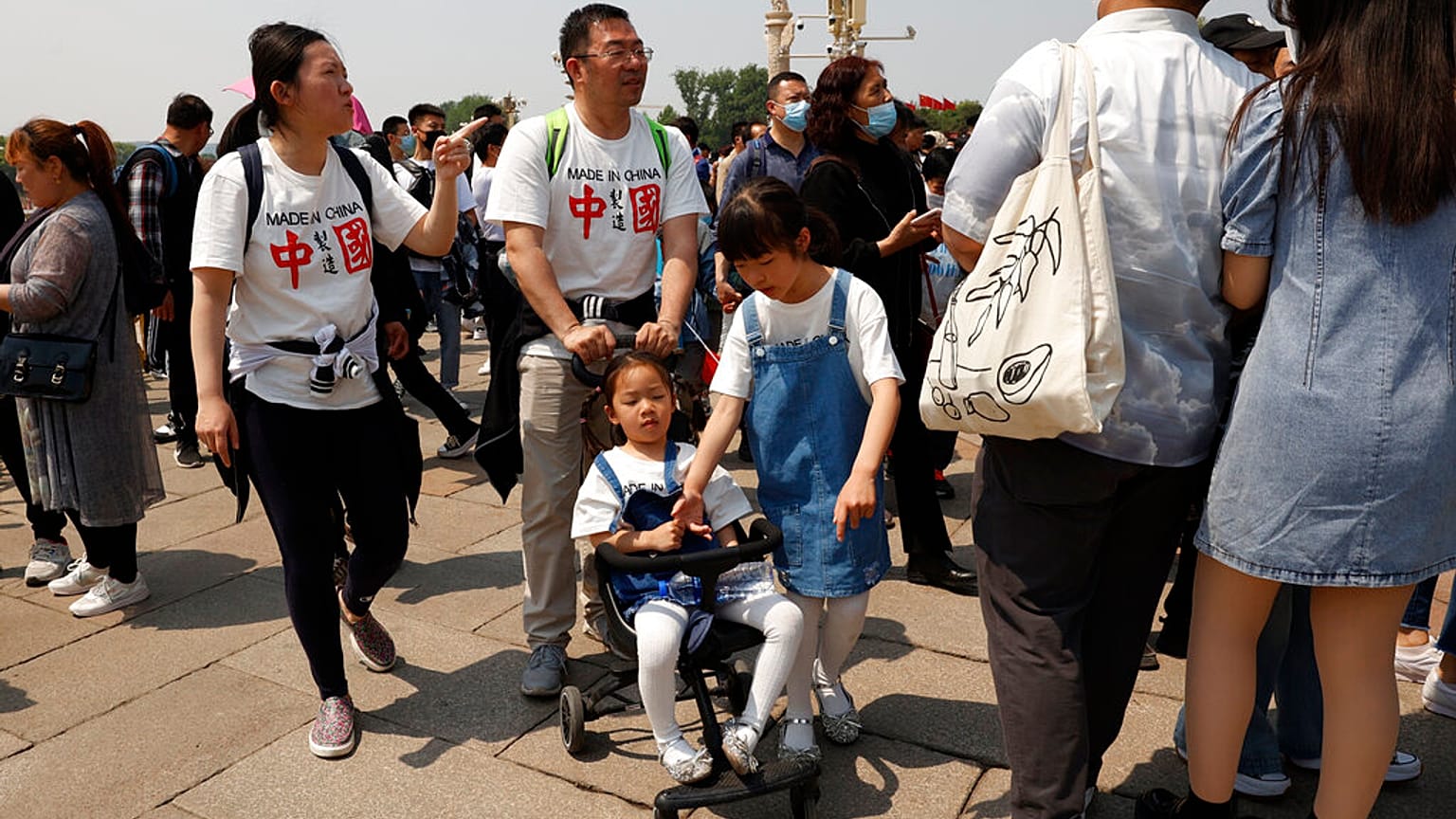 Residents wearing t-shirts which reads "Made In China" visit Tiananmen Gate with two children in Beijing