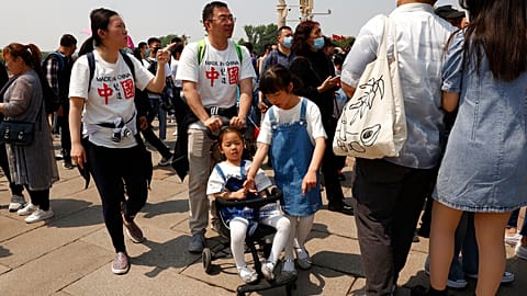 Residents wearing t-shirts which reads "Made In China" visit Tiananmen Gate with two children in Beijing