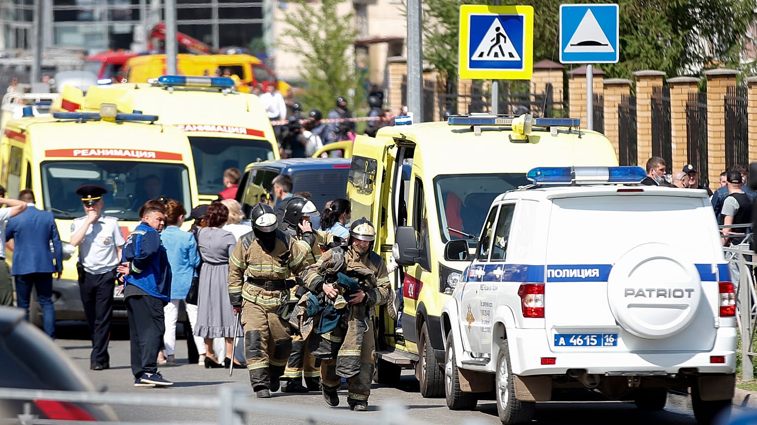 Los bomberos pasan por delante de ambulancias y coches de policía y un camión aparcado en una escuela después de un tiroteo en Kazán, Rusia, el martes 11 de mayo de 2021.
