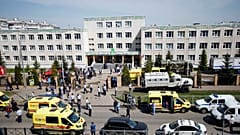 Ambulances and police cars and a truck are parked at a school after a shooting in Kazan, Russia, Tuesday, May 11, 2021. 