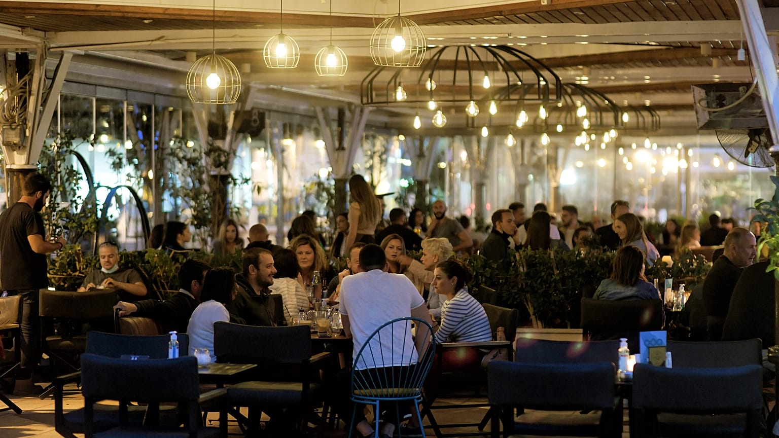 Κόσμος κάθεται σε καταστήματα εστίασης, σε εξωτερικό χώρο, στην Κόρινθο