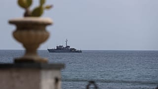 An Italian navy ship patrols the waters in front of the Sicilian town of Taormina in the Mediterranean Sea.