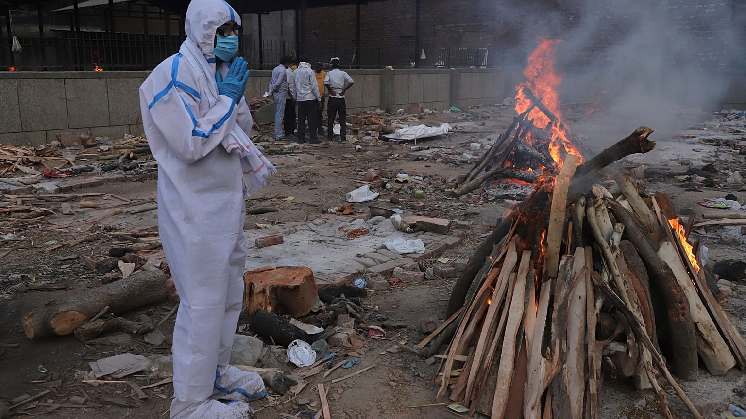 A man prays in front of the burning funeral pyre of his father who died of COVID-19, at a crematorium in New Delhi, India, May 11, 2021.