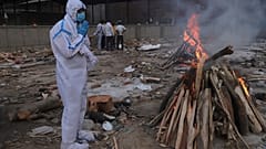 A man prays in front of the burning funeral pyre of his father who died of COVID-19, at a crematorium in New Delhi, India, May 11, 2021.