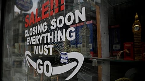 In this Friday, March 26, 2021 file photo, a shattered glass window fronts a closed souvenir store in central London, during England's third coronavirus lockdown