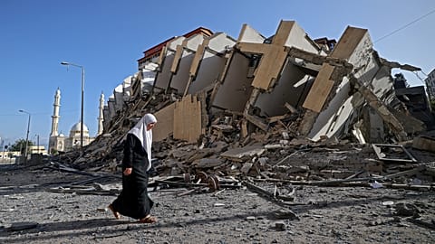 A Palestinian woman walks past a destroyed building in Gaza City.