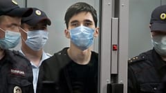 Ilnaz Galyaviyev, centre, stands behind a glass, surrounded by police officers during a hearing in a courtroom in Kazan, Russia, May 12, 2021. 