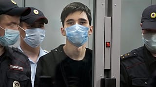 Ilnaz Galyaviyev, centre, stands behind a glass, surrounded by police officers during a hearing in a courtroom in Kazan, Russia, May 12, 2021. 
