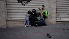 İsrail'in Gazze'ye yönelik hava bombardımanında evleri bombalanan bir aile, yol kenarında beklerken
