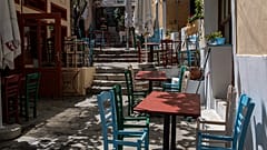 Chairs with a seat removed are placed around tables at a closed restaurant in the Athens' historic Plaka district, on Friday, April 30, 2021