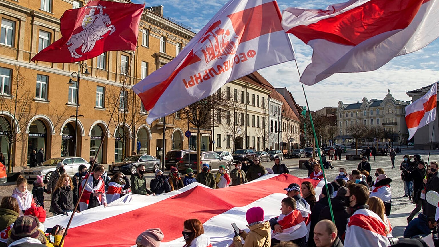 Belarusian people carry a giant historical flag of Belarus during a protest demanding freedom for political prisoners in Belarus at the Rotuses Square in Vilnius, Lithuania
