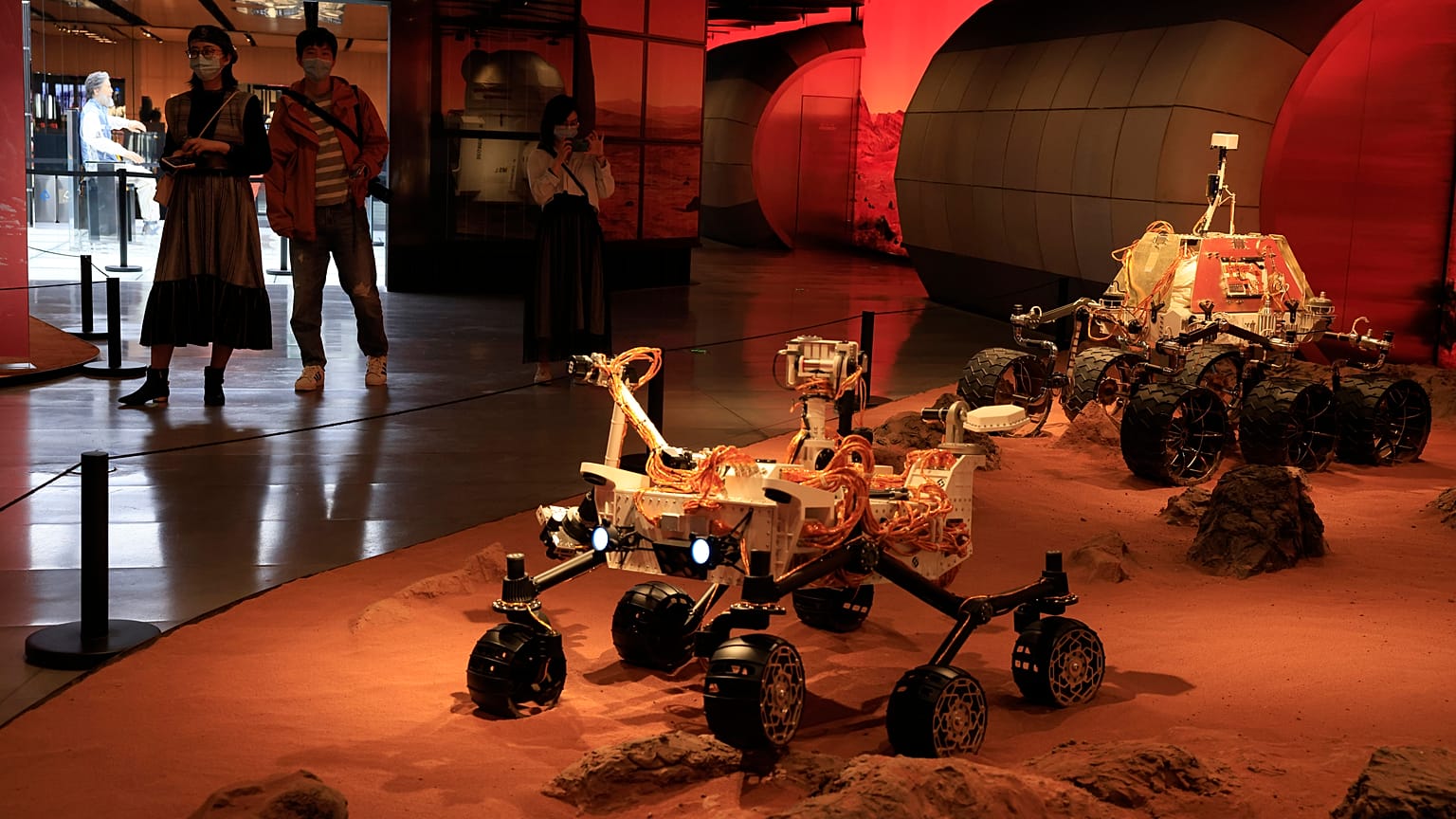 Visitors pass by an exhibition depicting rovers on Mars in Beijing on Friday, May 14, 2021. 