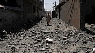 رجل يمشي فوق ركام مبنى دمره القصف الإسرائيلي  