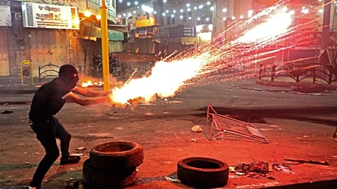 A Palestinian protester launches flares amid clashes with Israeli soldiers in the city center of Hebron in the occupied West Bank.