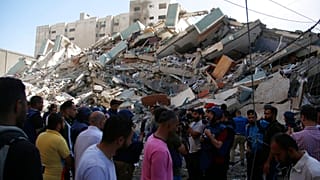 People gather at in front of a building housing AP office and other media in Gaza City 