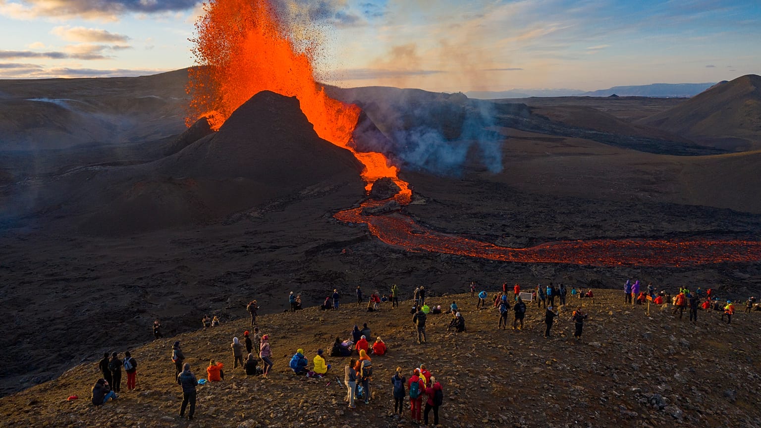People watch as lava flows from an eruption from the Fagradalsfjall volcano on the Reykjanes Peninsula in southwestern Iceland on Tuesday, May 11, 2021. 