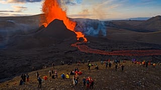 People watch as lava flows from an eruption from the Fagradalsfjall volcano on the Reykjanes Peninsula in southwestern Iceland on Tuesday, May 11, 2021. 