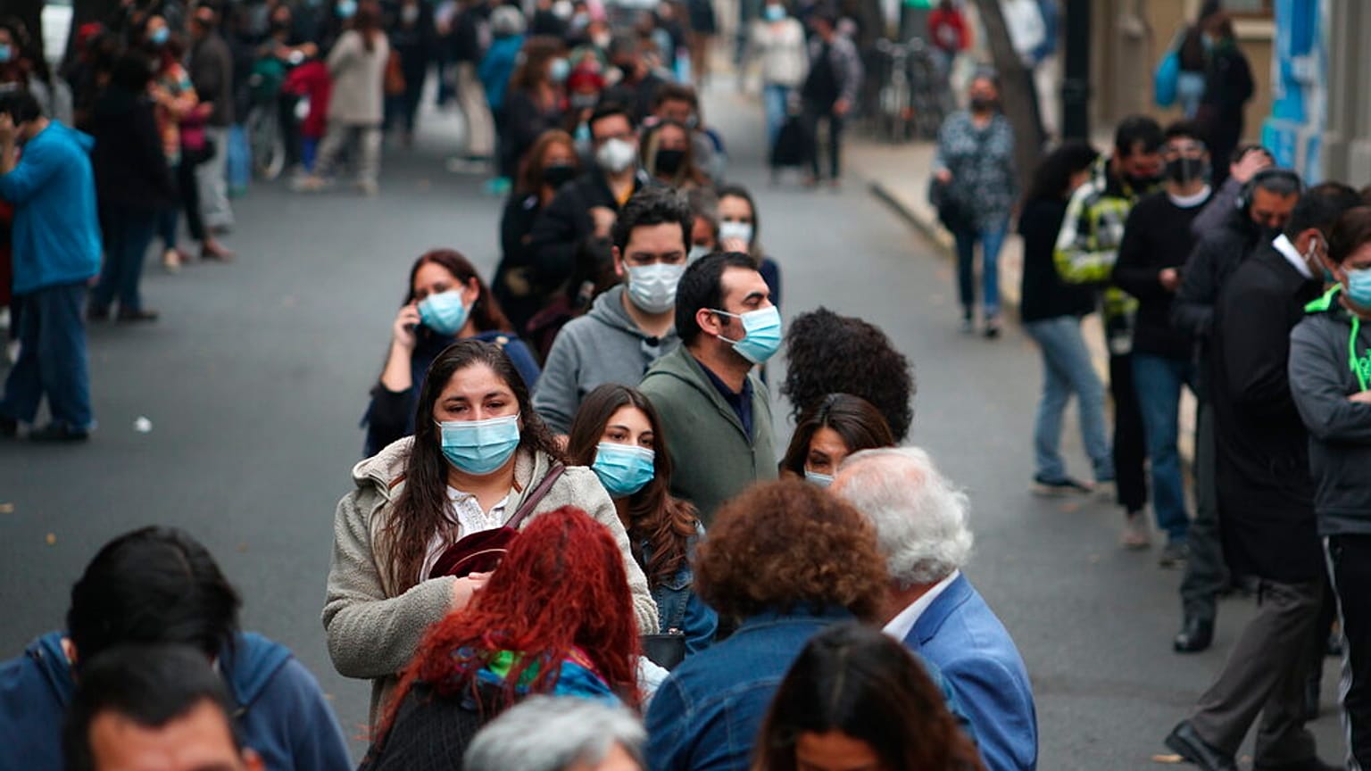 Cientos de personas aguardan en largas filas el momento de entrar en un colegio electora len Santiago de Chile.