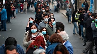 Cientos de personas aguardan en largas filas el momento de entrar en un colegio electora len Santiago de Chile.