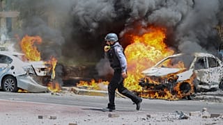 یک آتش‌نشان اسرائیلی در اطراف خودرویی که به دلیل برخورد راکت حماس آتش گرفته است. اشکلون، اسرائیل. 