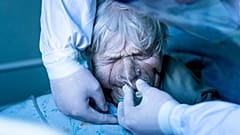 A medic wearing a special suit against coronavirus adjusts a coronavirus patient's oxygen mask at the intensive care unit at a hospital in the mining town of Selydove, Ukraine