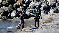 Des membres de la garde civile espagnole prenant en charge un migrant arrivant par la mer dans l'enclave de Ceuta, le 17 mai 2021 