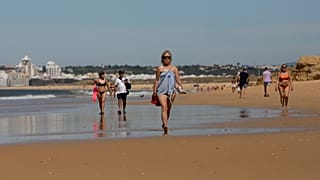 Turistas pasean por la playa en el Algarve