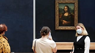 Visitante posa com máscara em frente à Mona Lisa, no Museu do Louvre