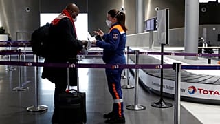 A member of Civil Protection checks air travellers documents at Paris Charles de Gaulle airport