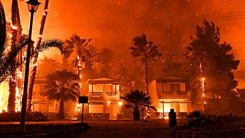 Fire burns among houses during a wildfire in the village of Schinos, near Corinth, Greece, late Wednesday, May 19, 2021