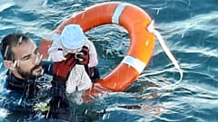 a member of the civil guard rescues a baby that was separated from its migrants parents, Spain