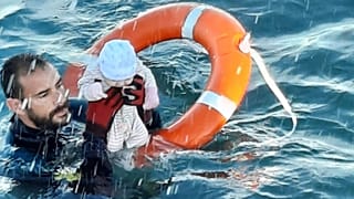 a member of the civil guard rescues a baby that was separated from its migrants parents, Spain