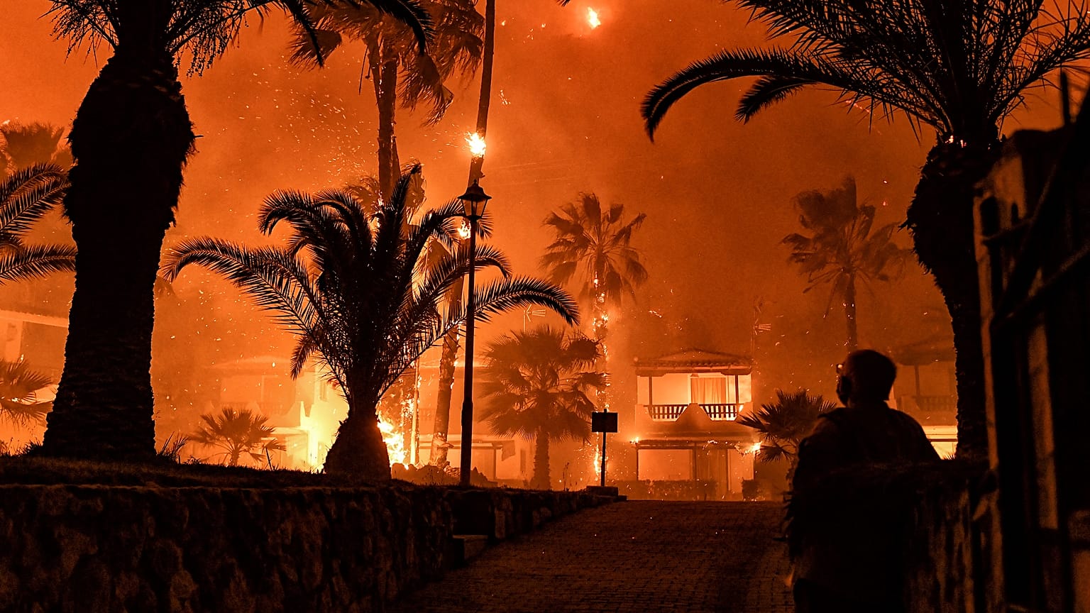 A man stands in front of a wild fire in Schinos, west of Athens, Greece. May 19, 2021