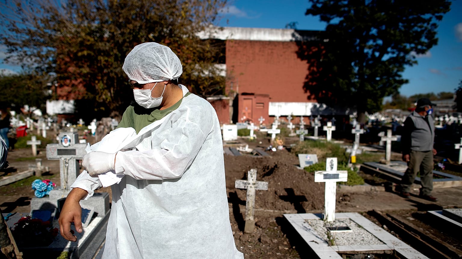 Un employé d'un cimetière argentin enlève sa blouse de protection après avoir déplacé un cercueil contenant une victime du Covid-19, à Buenos Aires, le 8 mai 2021.