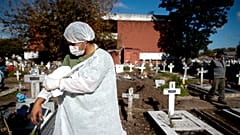 Un employé d'un cimetière argentin enlève sa blouse de protection après avoir déplacé un cercueil contenant une victime du Covid-19, à Buenos Aires, le 8 mai 2021.