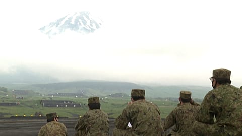 Members of self-defence forces watching exercises with Mount Fuji in the background