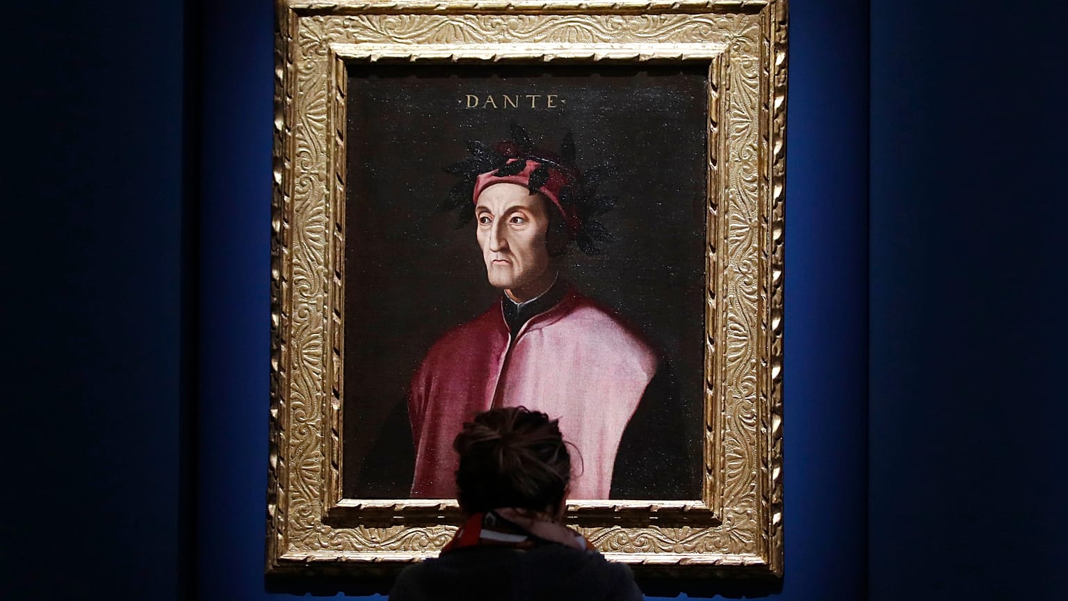 A woman looks at a portrait of poet Dante Alighieri at an exhibition, in Forlì, Italy, Saturday, May 8, 2021