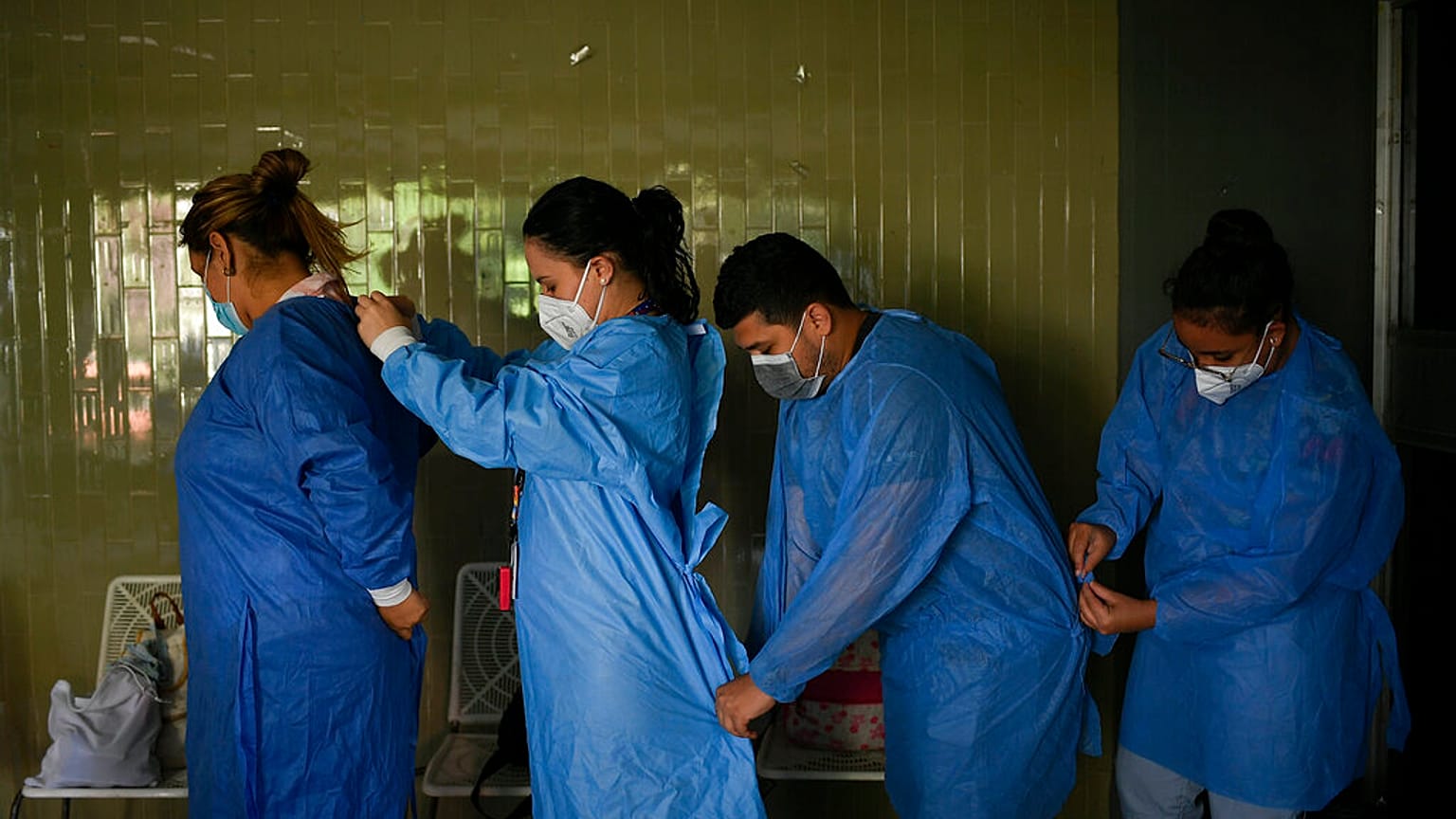 Government doctors put on protective gowns as they prepare to give free, rapid COVID-19 tests to residents who volunteer in the El Paraiso neighborhood of Caracas, Venezuela