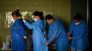 Government doctors put on protective gowns as they prepare to give free, rapid COVID-19 tests to residents who volunteer in the El Paraiso neighborhood of Caracas, Venezuela