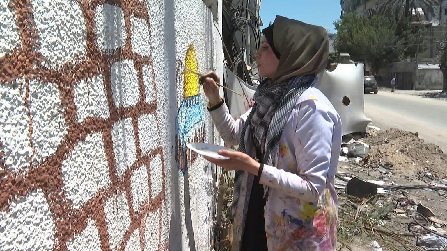فنانة فلسطينية ترسم على جدران مهدمة في غزة بعد القصف الإسرائيلي على القطاع المحاصر