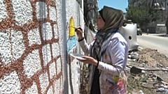 فنانة فلسطينية ترسم على جدران مهدمة في غزة بعد القصف الإسرائيلي على القطاع المحاصر
