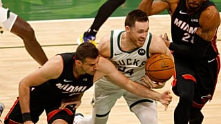 El escolta de los Milwaukee Bucks Pat Connaughton, en el centro, lucha por el balón contra los aleros de los Miami Heat 