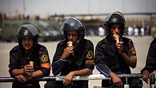 عناصر الشرطة المصرية بأكلون المثلجات أثناء حراسة محيط محكمة في القاهرة. 2012/05/02