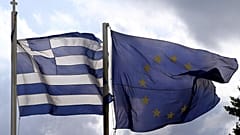 Οι σημαίες της Ελλάδας και της Ευρωπαϊκής Ένωσης ανεμίζουν με φόντο τον αττικό ουρανό.
