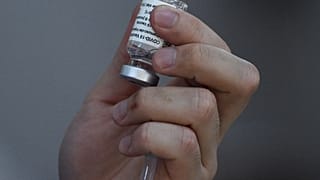 A health worker holds a vial of the AstraZeneca/Oxford Covid-19 coronavirus vaccine inside a Catholic church turned into a vaccination centre in Manila on May 21, 2021.